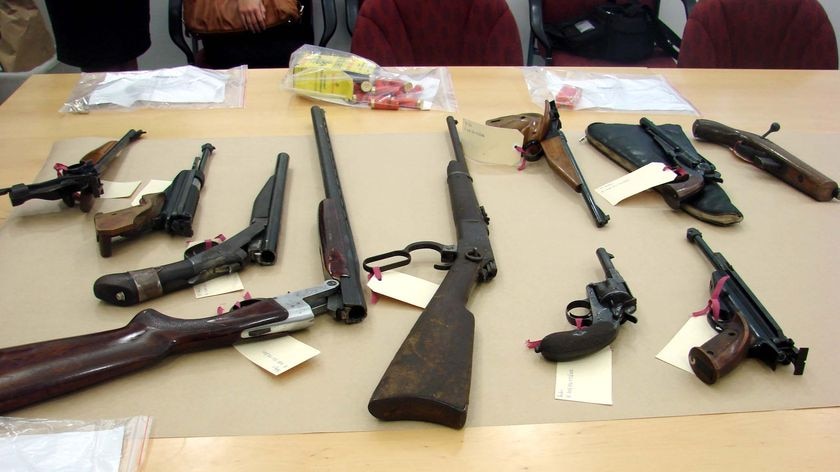 Firearms and ammunition are displayed to the media