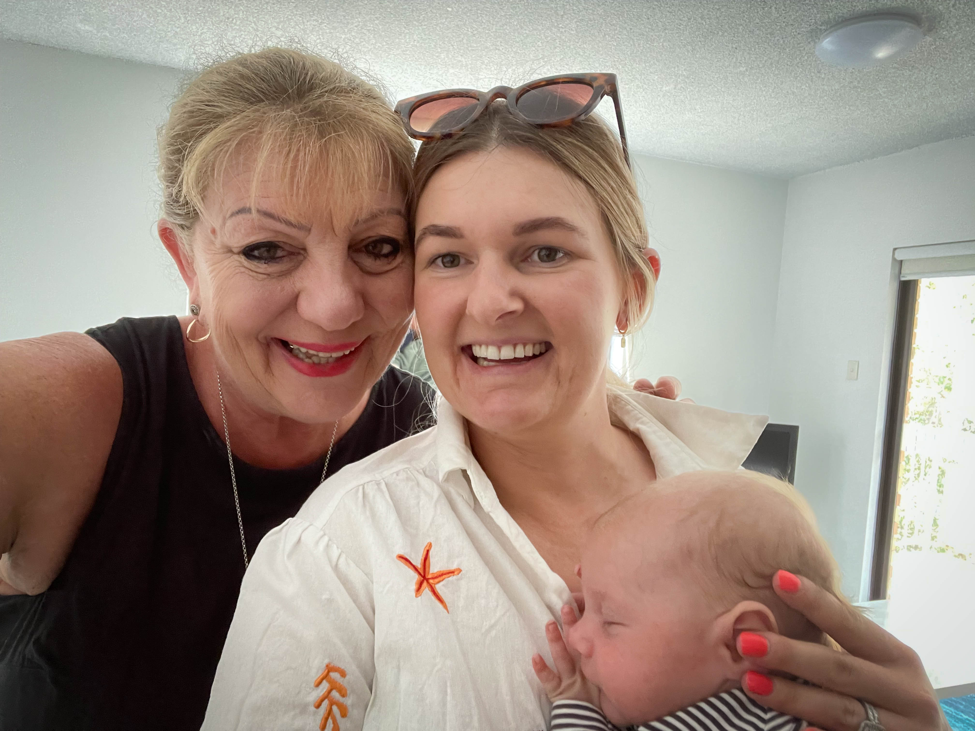 Two women with heads close together with woman on right holding a newborn baby