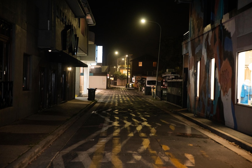 A street late at night with yellow and white markings and a single street light