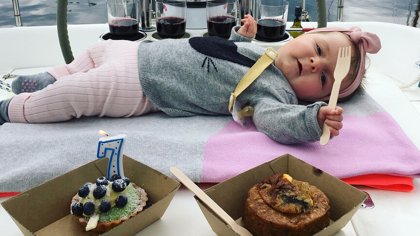 Mackenzie lying next to a cake to celebrate her seven months of life