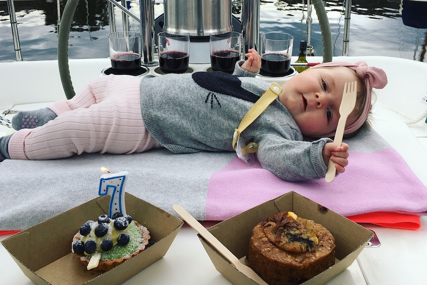 Mackenzie lying next to a cake to celebrate her seven months of life
