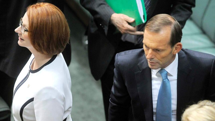 Julia Gillard walks past Tony Abbott