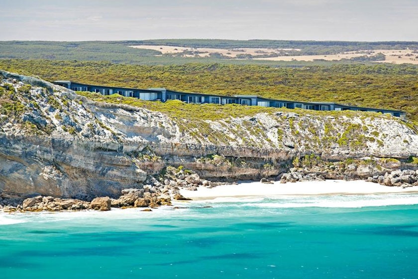 Luxury accommodation sitting on top of a cliff overlooking pristine water.