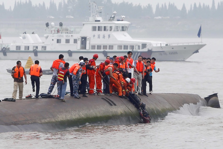 A man is pulled out alive by rescuers after a ferry sinks in the Yangtze River