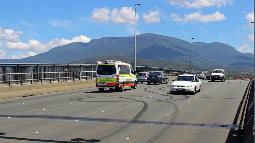 An ambulance passes burnout marks on the Tasman Bridge