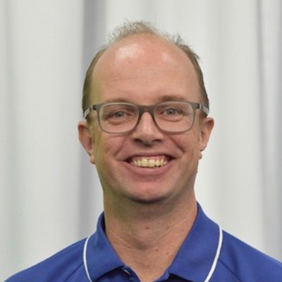 A bald man wearing glasses and a blue polo shirt