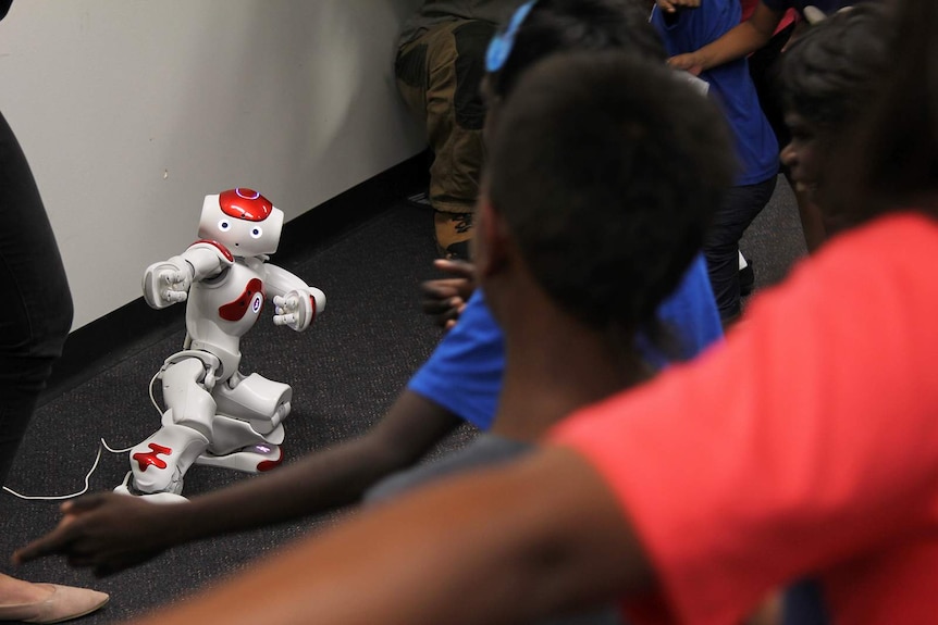 A robot dancing in the front of a classroom, with many arms visibly mimicking it.