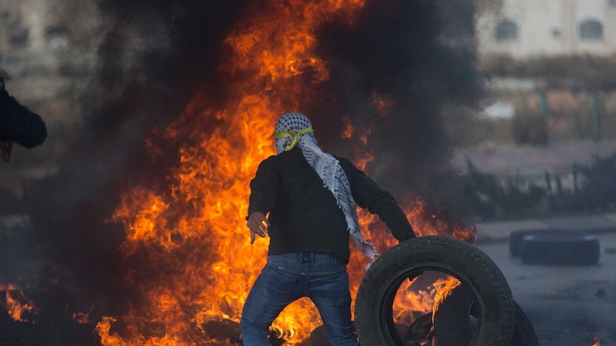 A Palestinian protester burns tires.