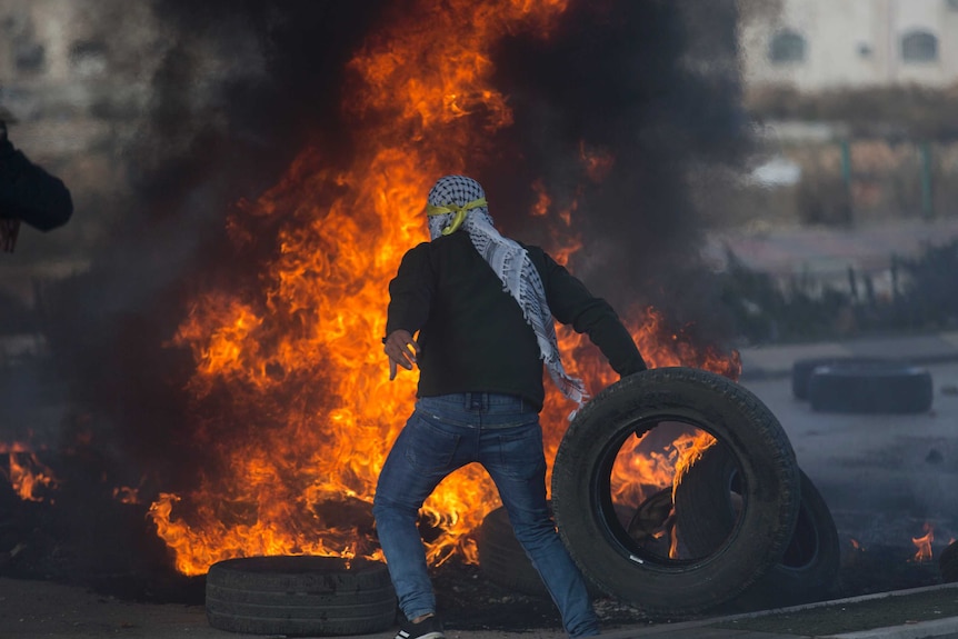 A Palestinian protester burns tires.