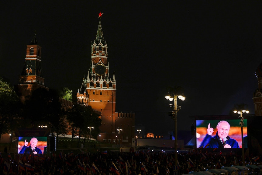 Russian President Vladimir Putin is seen on screens during a concert in Moscow.