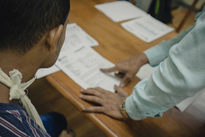 J Ravinthiran explains documents to a migrant worker