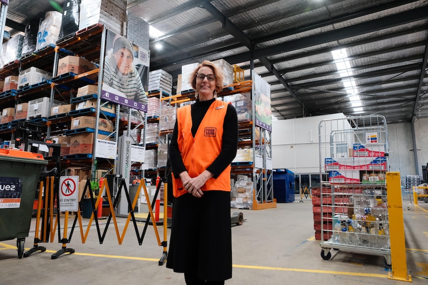 Sara stands in a food processing warehouse in a high-vis vest.