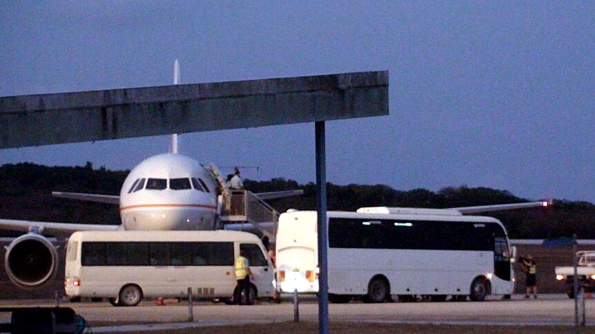 Buses carrying Sri Lankan asylum seekers sit on the tarmac next to a plane on Christmas Island.