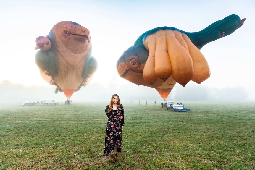 Patricia Piccinini with two large whale-shaped balloons behind her.