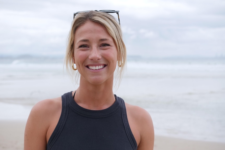 Mujer rubia en la playa sonriendo.