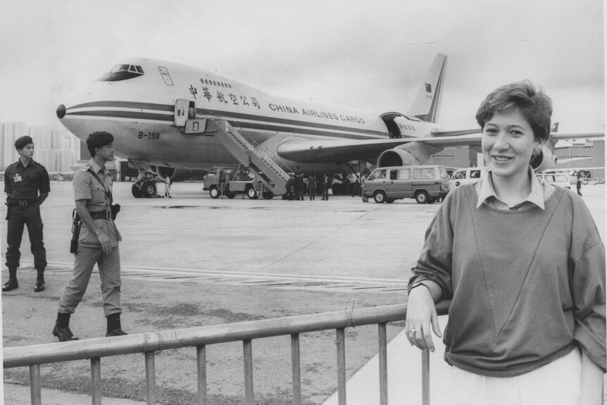 A black and white image of a woman standing in front of a China Airlines plane