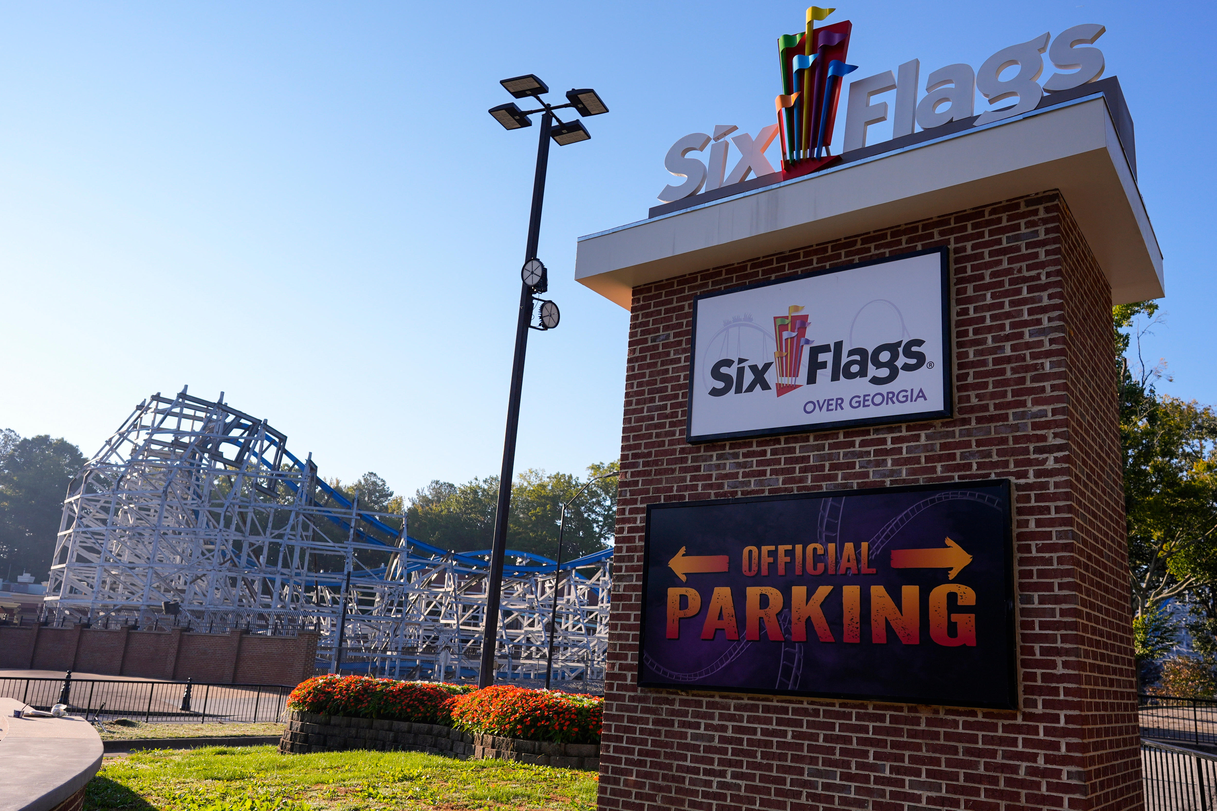 A brick sign with the name 'Six Flags over Georgia' and parking in front of a roller coaster.