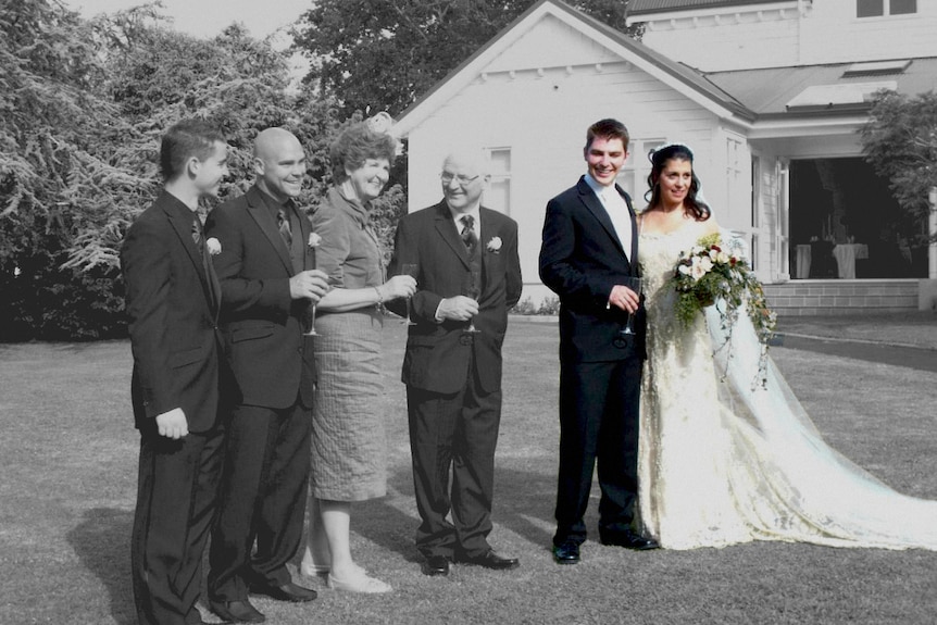 A happy wedding couple posing for a photo with their family.