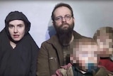 Caitlan Coleman wearing a hijab talks in the video while her husband Joshua Boyle looks ahead holding two children