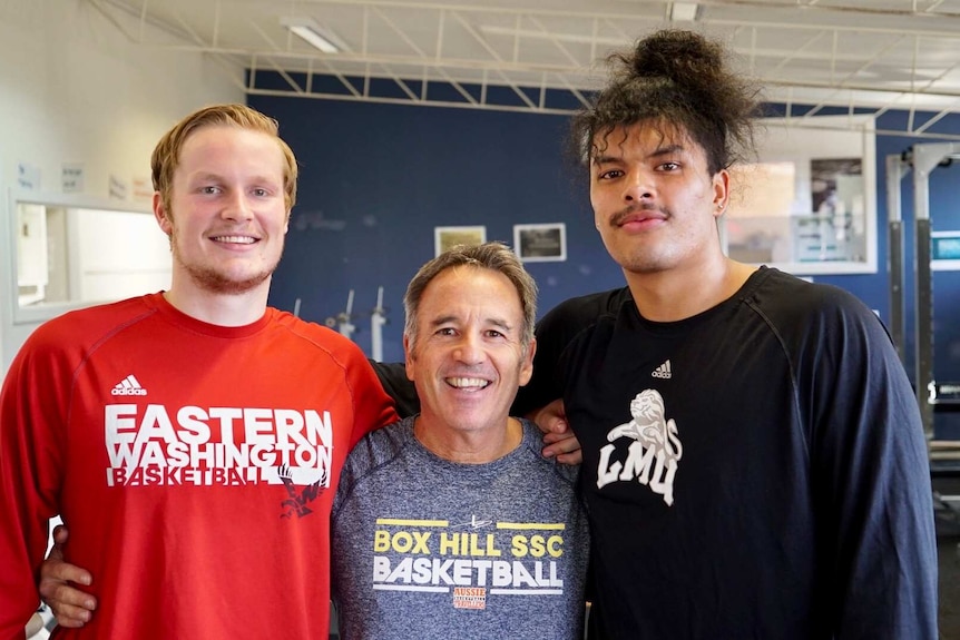 Tyler Robertson, Kevin Goorjian and Keli Leaupepe pose for a photo in the school gym