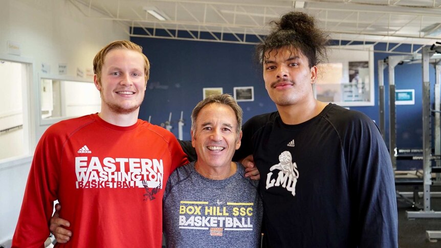 Tyler Robertson, Kevin Goorjian and Keli Leaupepe pose for a photo in the school gym