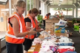 Teresa Robertson and Liza Huston fold and sort donations.