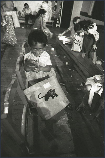 A small boy looks at the camera with a present. 