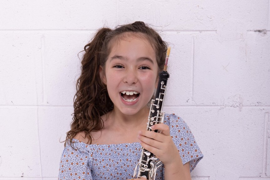 A young girl smiling while holding an oboe