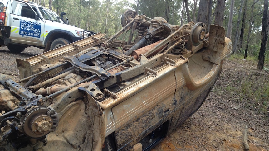 An upturned dumped four wheel drive with no wheels.