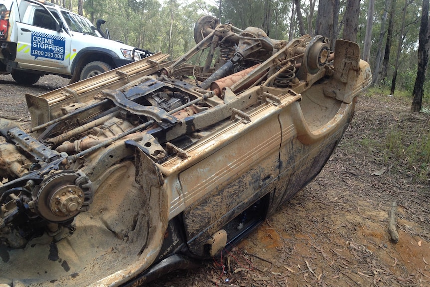 An upturned dumped four wheel drive with no wheels.