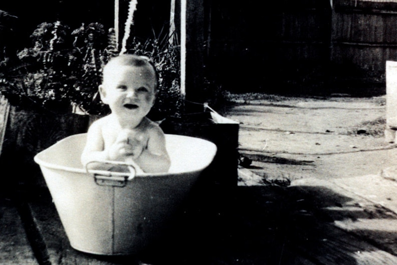 A black and white photo shows Bob Hawke as a toddler sitting in a tin bath in the backyard of his Bordertown home in SA.