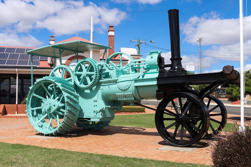 A turquoise tractor on display in a town centre