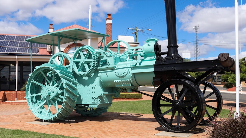 A turquoise tractor on display in a town centre.