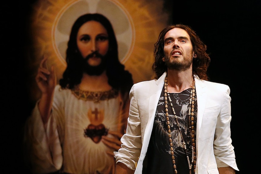 A man looking up and posing, with an image of Jesus visible behind him