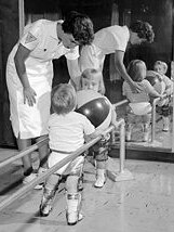 A physical therapist assists two polio-stricken children.