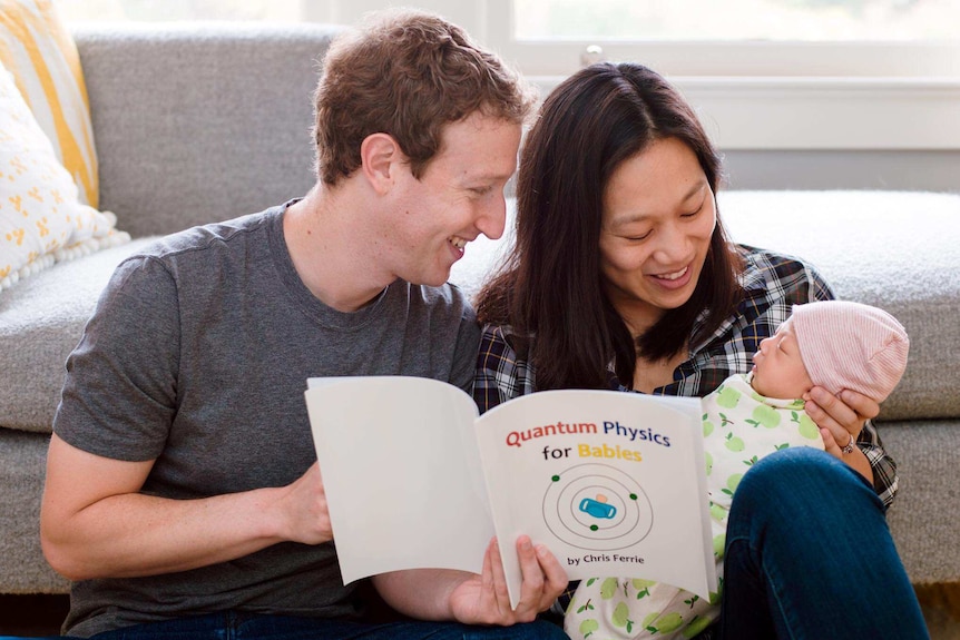 Mark Zuckerberg and wife Priscilla Chan sit on a couch next to each other while reading to their son Max.