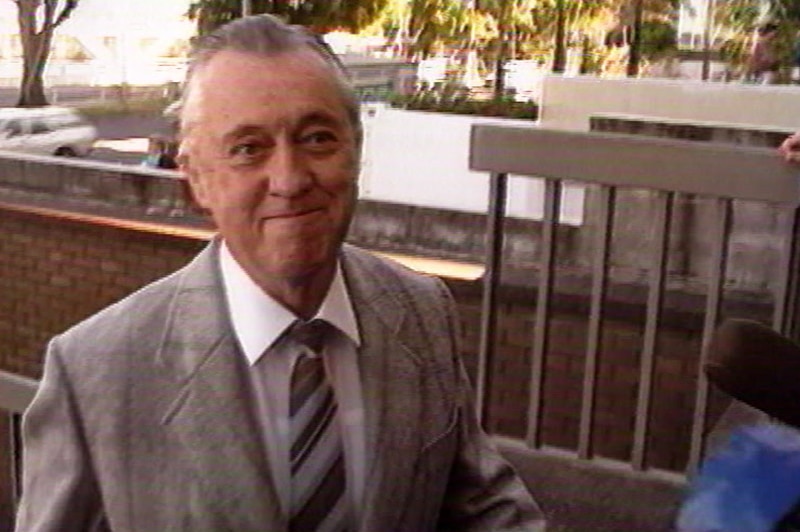 Former Queensland police commissioner Terry Lewis dressed in a suit, walks up some stairs in Brisbane.