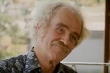 A 1970s TV still of an older, balding man with a moustache and wiry eyebrows