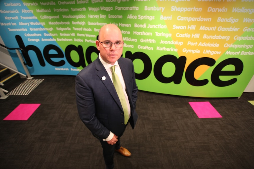Man standing in front of a hyper colour Headspace sign.