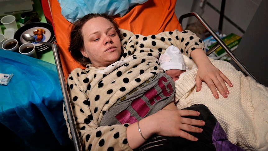 A mother and newborn lie on a hospital bed