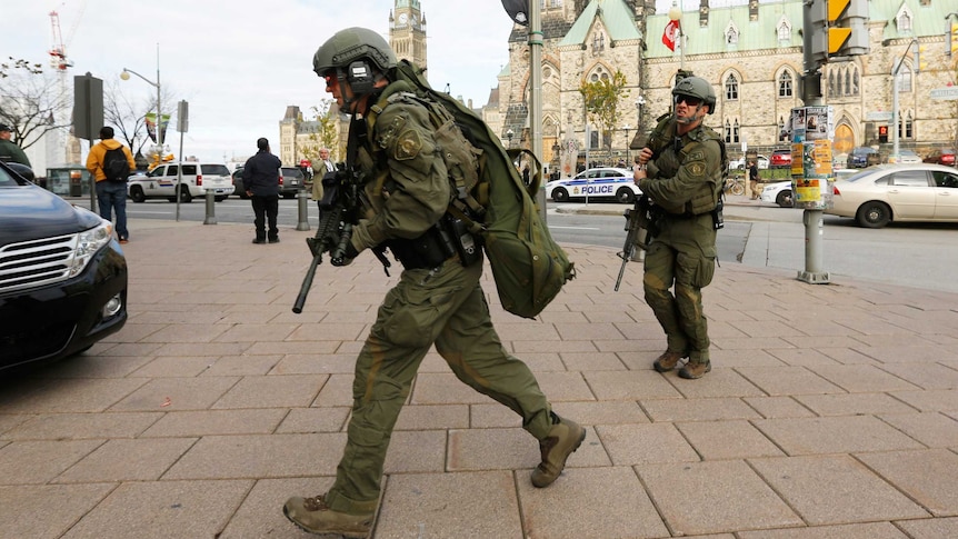 Armed officers head towards Parliament Hill following a shooting in Ottawa, Canada
