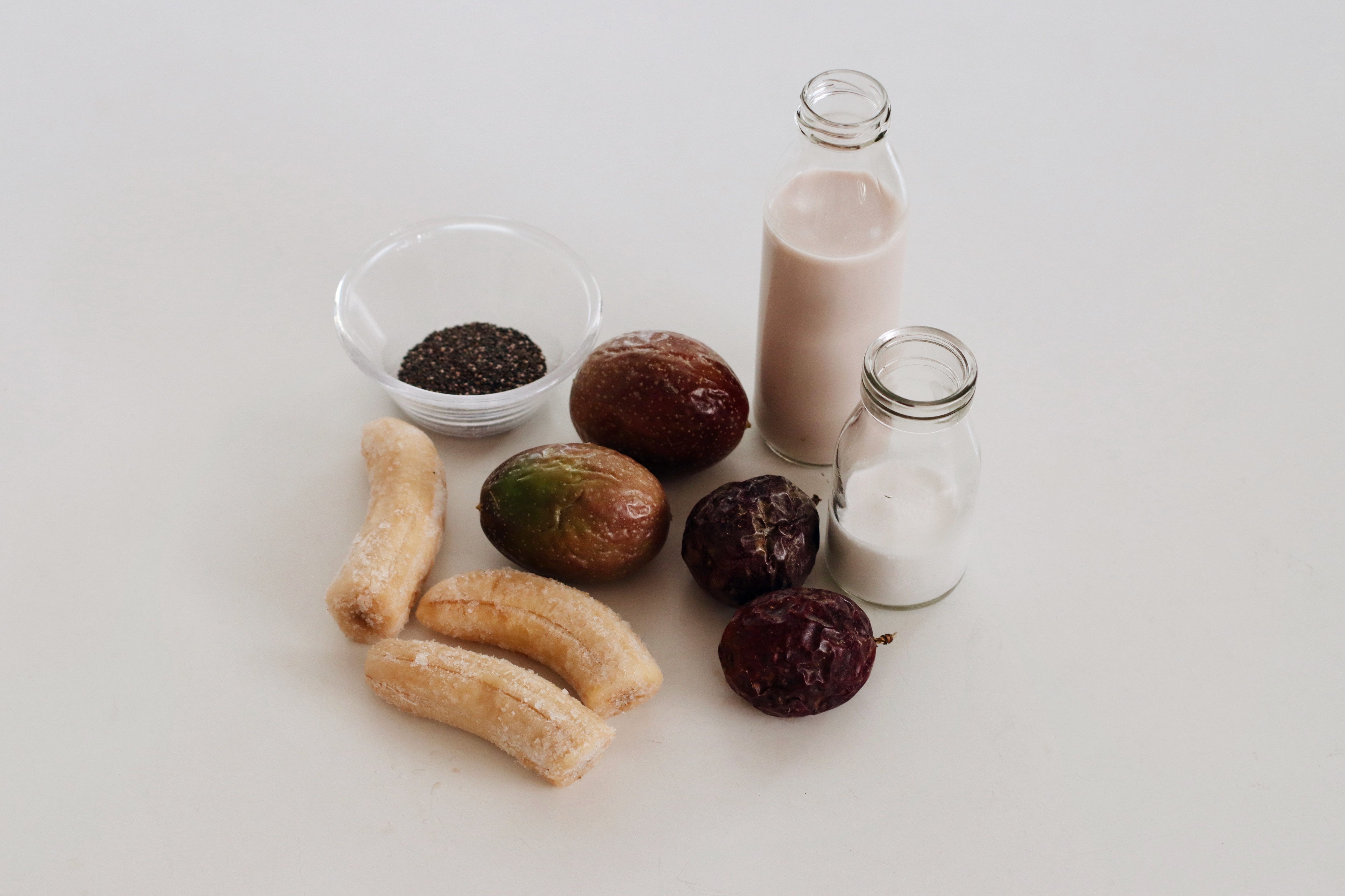 Smoothie ingredients on the kitchen bench including banana, passionfruit, kefir, milk and chia seeds.