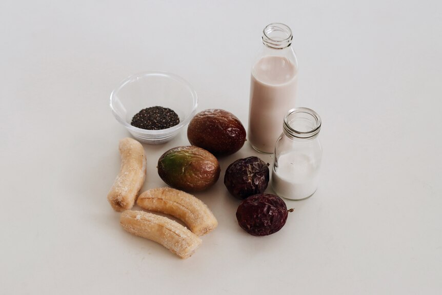 Smoothie ingredients on the kitchen bench including banana, passionfruit, kefir, milk and chia seeds.