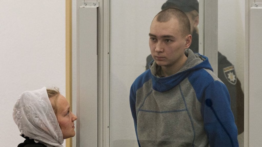 Russian soldier Vadim Shishimarin stands and listens to a translator during his trial on charges of war crimes