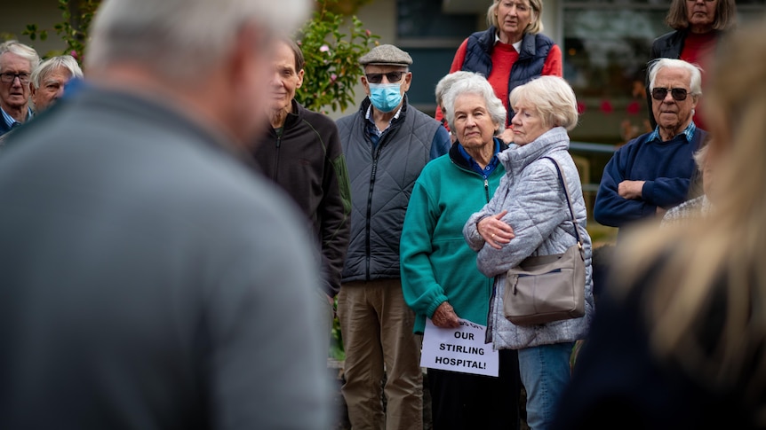 A group of residents gathered outside a hospital, looking angry