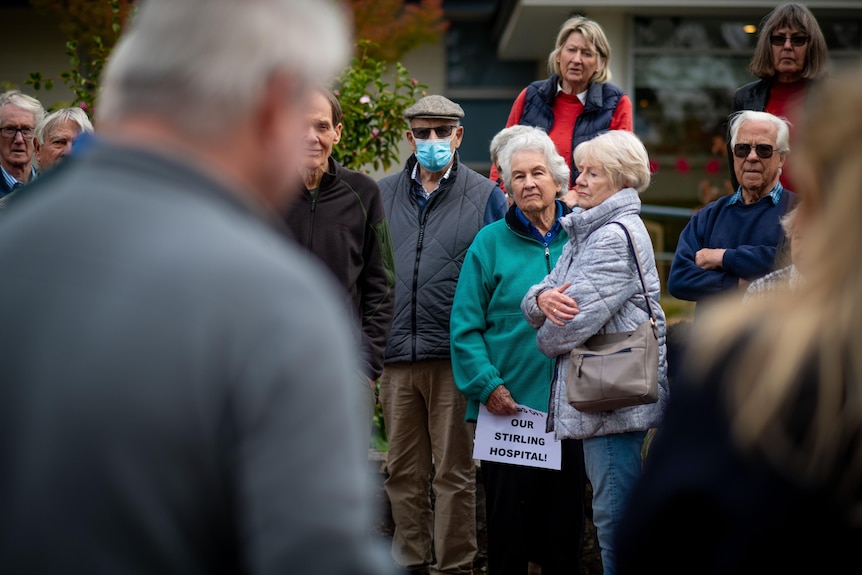A group of residents gathered outside a hospital, looking angry