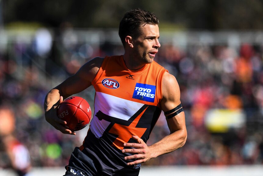 Brett Deledio holds the ball in his right hand playing for the Giants against the Demons.