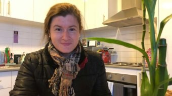 A women holding a mug in a kitchen.