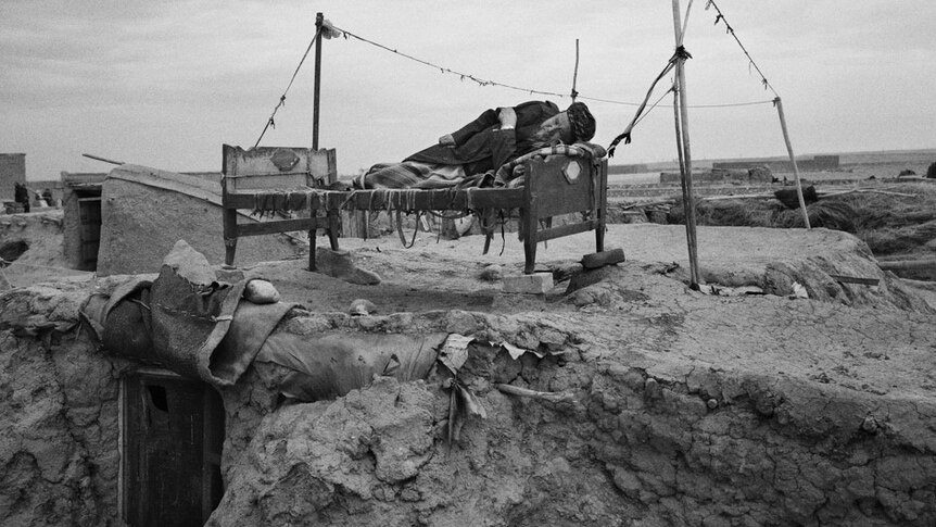 A man lies on a bed in the Qualin Bafan camp,  located on a desolate, windswept plain in northern Afghanistan.
