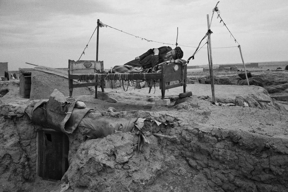 A man lies on a bed in the Qualin Bafan camp,  located on a desolate, windswept plain in northern Afghanistan.